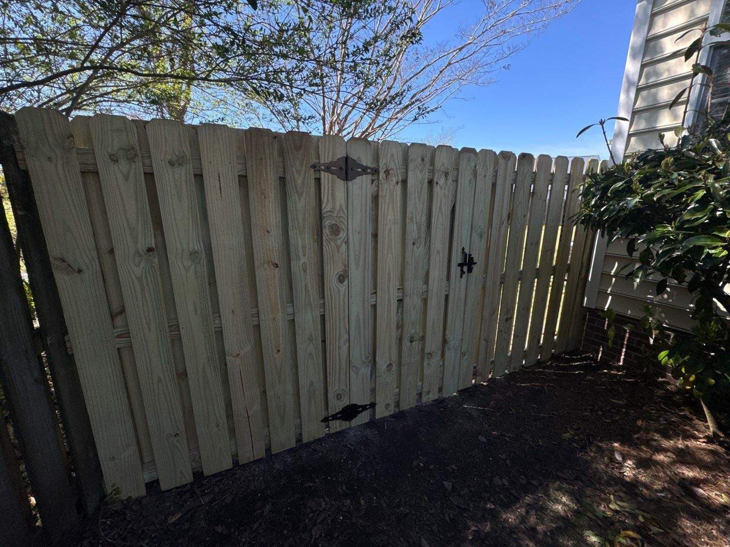 Shadowbox wood fence with custom drive gate and black hardware in the Wilmington, NC area