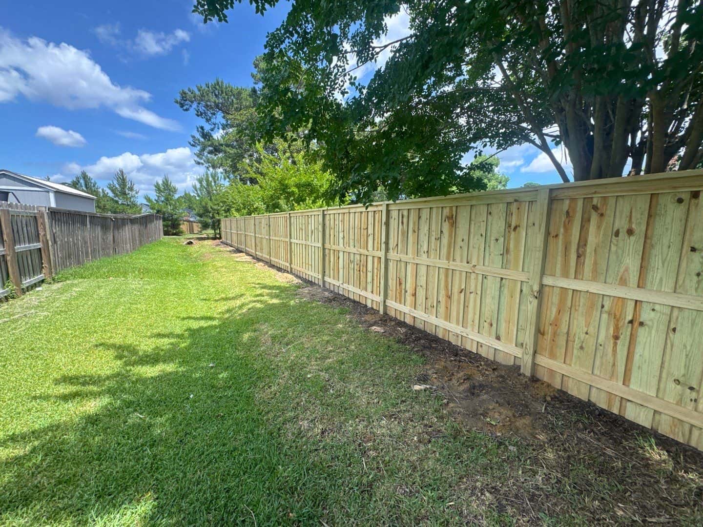 A long, straight run of new wood privacy fence built by Kona Fence Co in the Wilmington, NC area